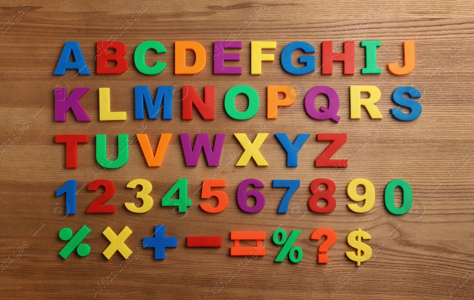 Photo of Plastic magnetic letters, numbers and math symbols on wooden background, top view