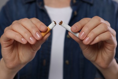 Photo of Stop smoking concept. Woman holding pieces of broken cigarette, closeup