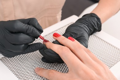 Photo of Professional manicurist working with client at table, closeup