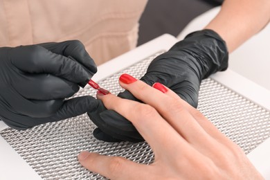 Professional manicurist working with client at table, closeup