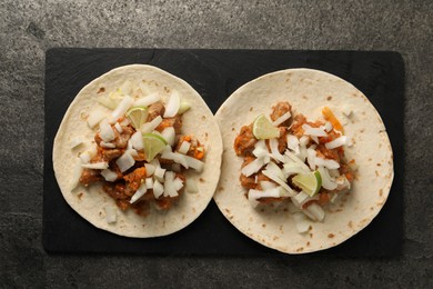 Delicious tacos with vegetables, meat and lime on grey textured table, top view