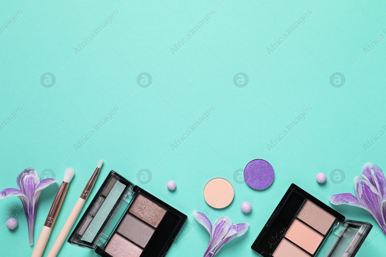 Photo of Flat lay composition with different makeup products and beautiful flowers on light turquoise background. Space for text