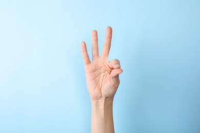 Photo of Woman showing number nine on color background, closeup. Sign language