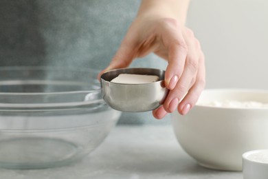Photo of Woman with yeast near bowl at light grey marble table, closeup. Cooking traditional grissini