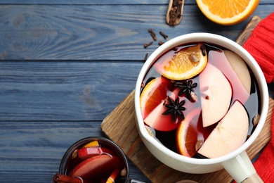 Photo of Delicious mulled wine and ingredients on blue wooden table, flat lay. Space for text