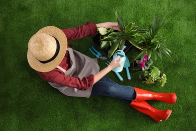 Photo of Woman taking care of plant on green grass, top view. Home gardening