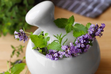 Photo of Mortar with fresh lavender flowers, herbs and pestle on table, closeup