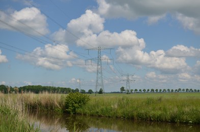 Photo of Modern high voltage towers in field on sunny day