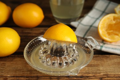 Photo of Squeezer with juice and lemons on wooden table