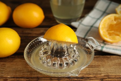 Squeezer with juice and lemons on wooden table