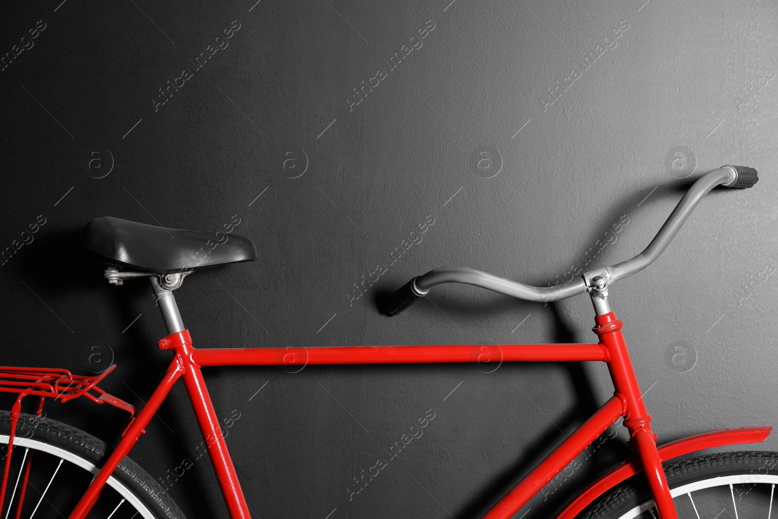 Photo of Red bicycle hanging on black wall, closeup