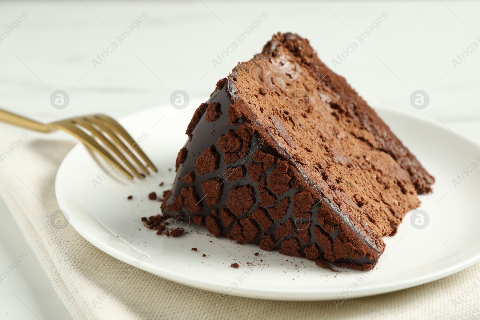 Photo of Piece of delicious chocolate truffle cake and fork on table, closeup