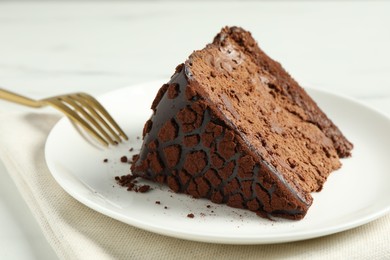 Piece of delicious chocolate truffle cake and fork on table, closeup