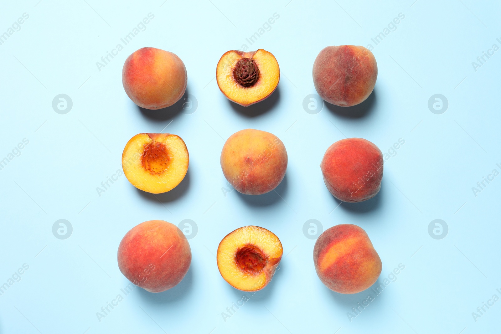 Photo of Cut and whole fresh ripe peaches on light blue background, flat lay