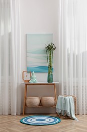 Console table with bamboo and Buddha statue near light wall indoors. Interior design