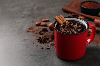Photo of Yummy hot chocolate with cinnamon and anise in mug on grey table. Space for text