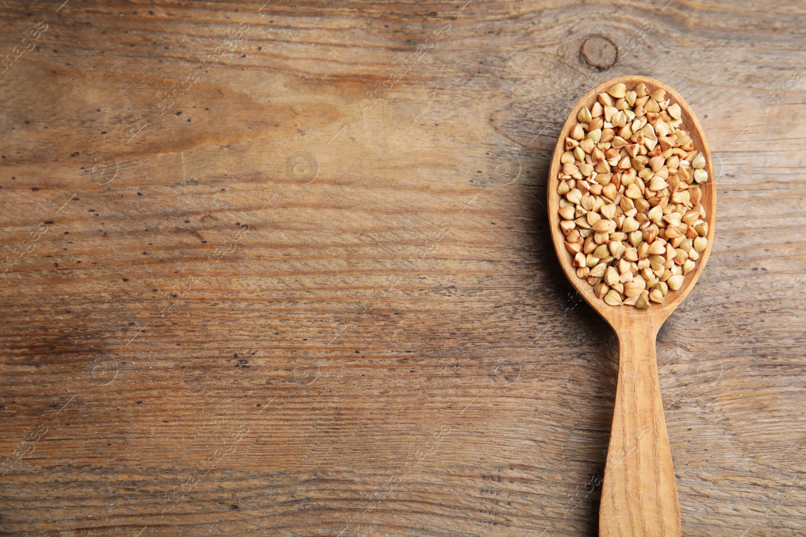 Photo of Spoon with green buckwheat on wooden table, top view. Space for text