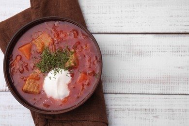 Photo of Tasty borscht with sour cream in bowl on white wooden table, top view. Space for text