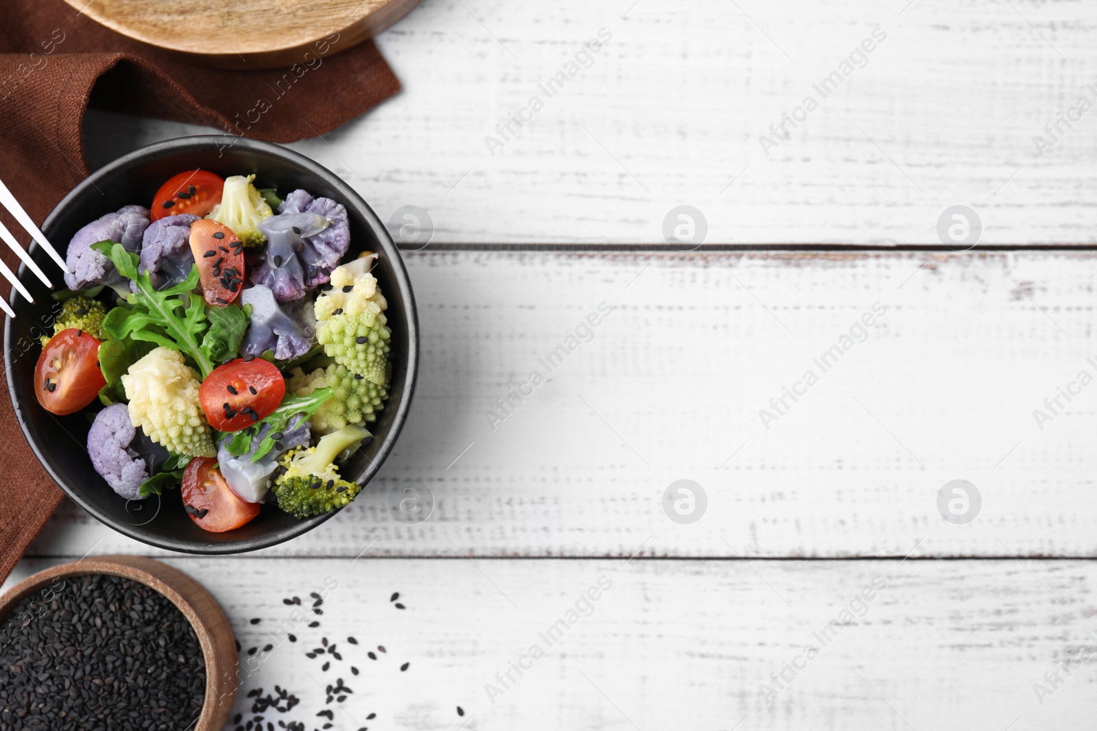 Photo of Delicious salad with cauliflower and tomato served on white wooden table, flat lay. Space for text