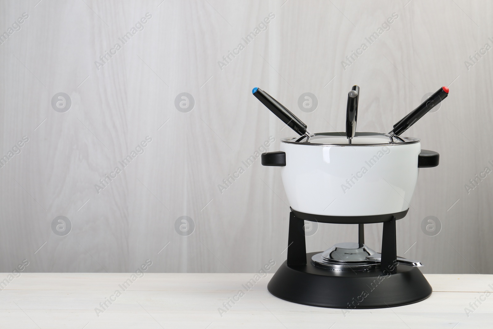 Photo of Fondue set on white wooden table, space for text