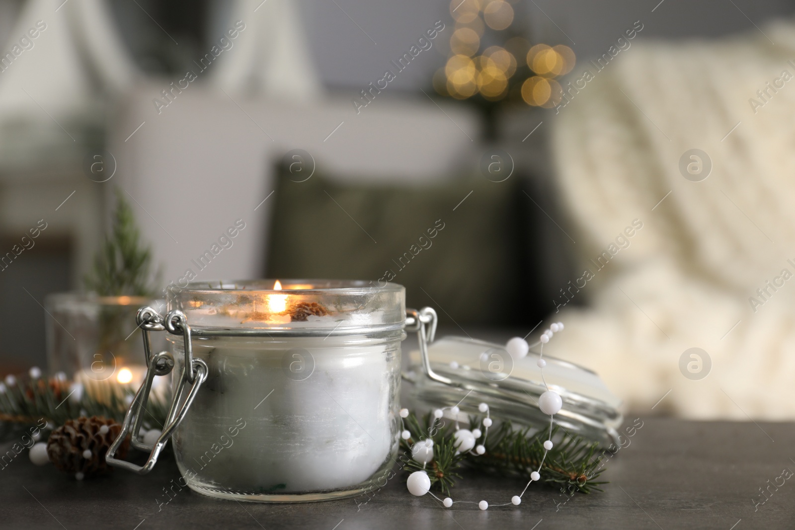 Photo of Burning scented conifer candle and Christmas decor on grey table indoors. Space for text