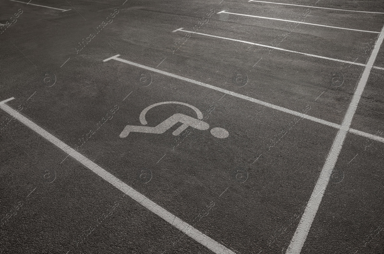 Image of Car parking lot with white marking lines and wheelchair symbol  