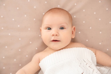 Photo of Adorable baby girl lying in bed, top view