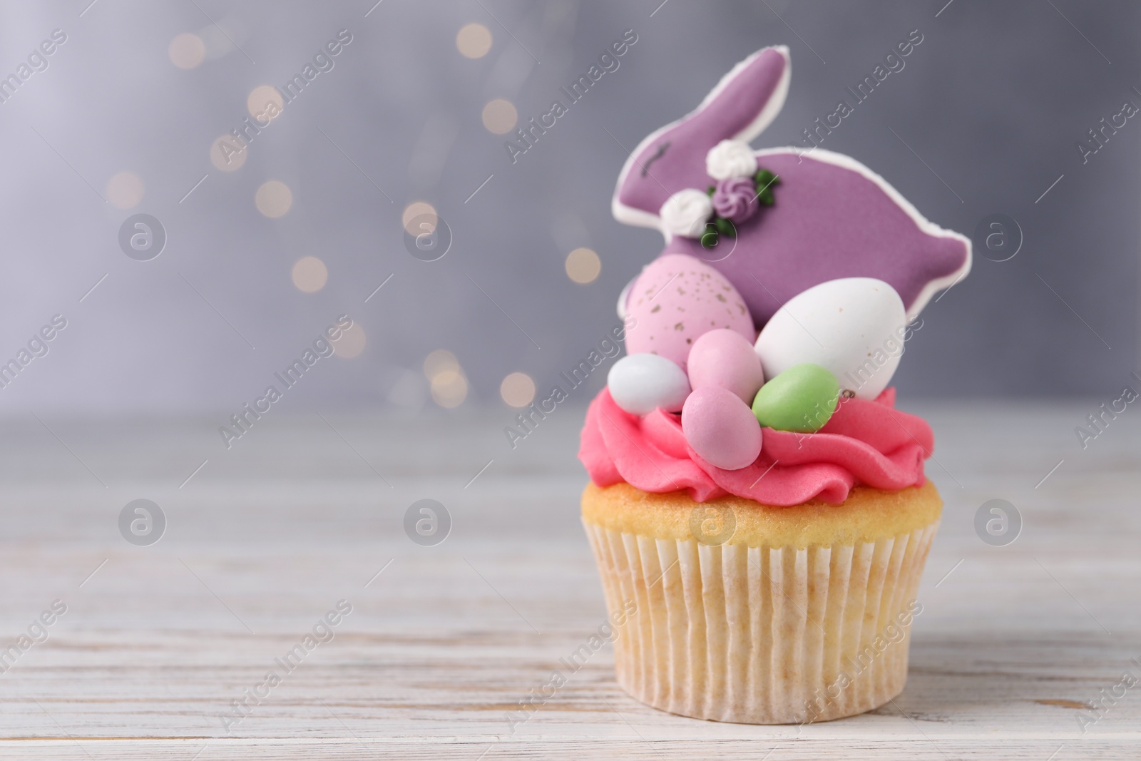 Photo of Tasty cupcake with Easter decor on wooden table, space for text