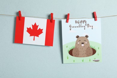 Photo of Happy Groundhog Day greeting card and Canada flag hanging against light background