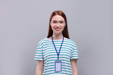 Young woman with vip pass badge on light grey background