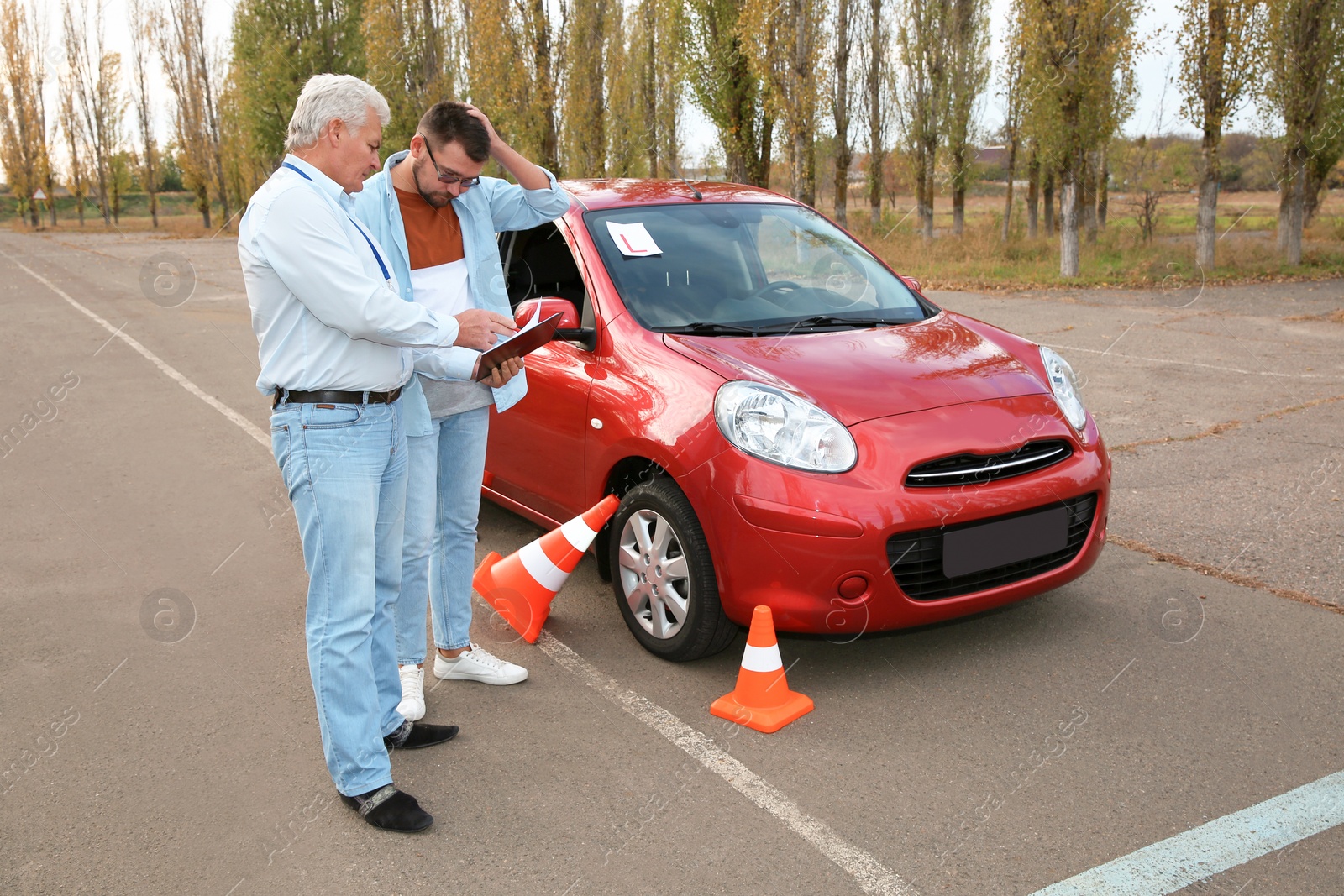 Photo of Senior instructor and man near car outdoors. Passing driving license exam