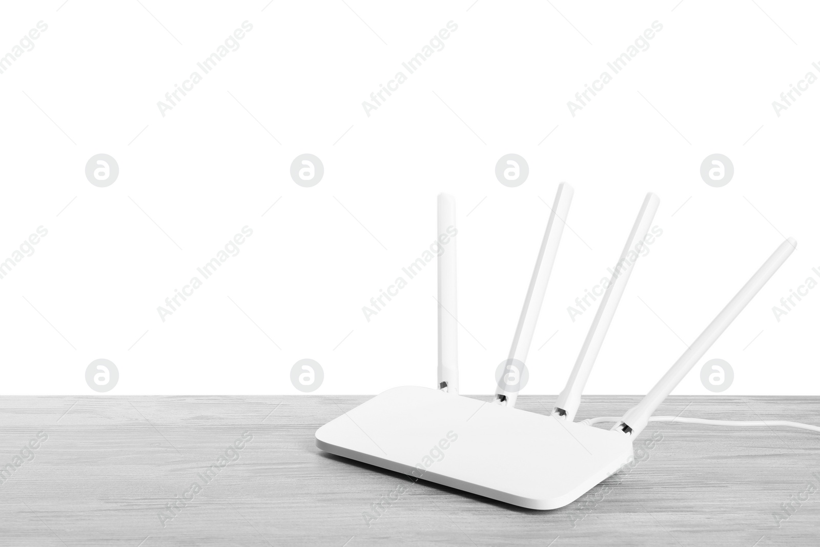 Photo of New modern Wi-Fi router on light wooden table against white background. Space for text