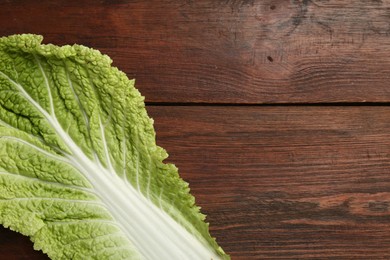 Photo of Fresh leaf of Chinese cabbage on wooden table, top view. Space for text