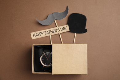 Photo of Flat lay composition with wristwatch in gift box on brown background. Happy Father;s day