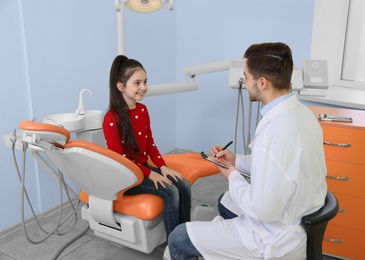 Photo of Professional dentist and little patient in modern clinic