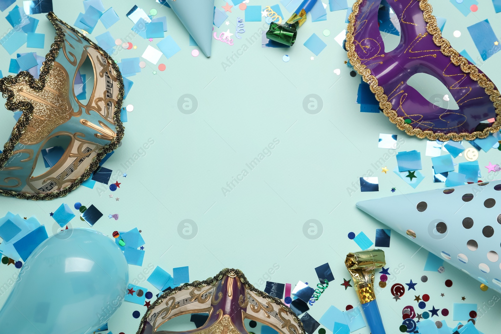 Photo of Frame of beautiful carnival masks and party decor on light blue background, flat lay. Space for text