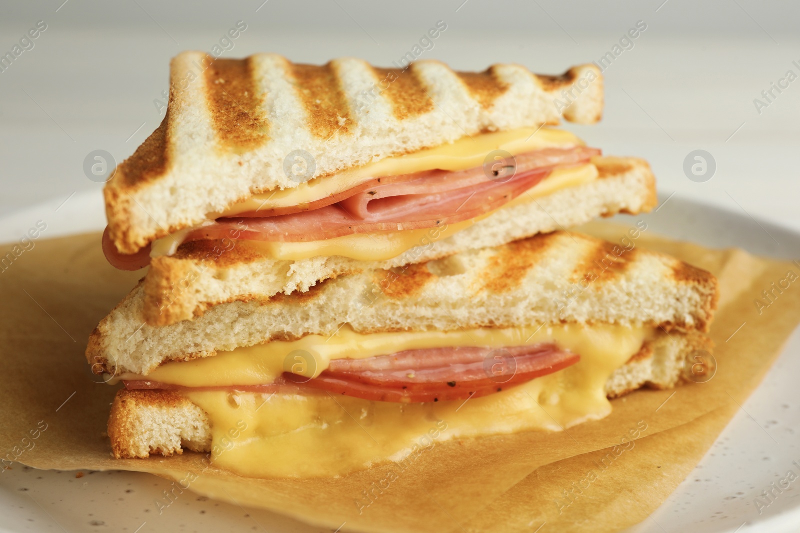 Photo of Tasty sandwiches with ham and melted cheese on plate, closeup