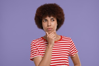 Portrait of thoughtful young woman on purple background