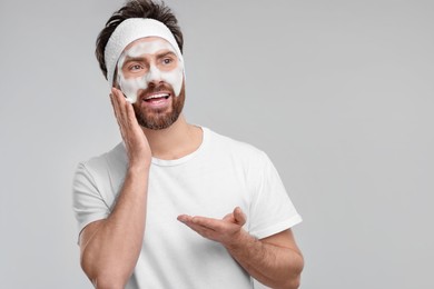 Photo of Man with headband washing his face on light grey background, space for text