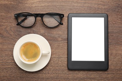 Photo of E-book reader, cup of coffee and glasses on wooden table, flat lay. Space for text