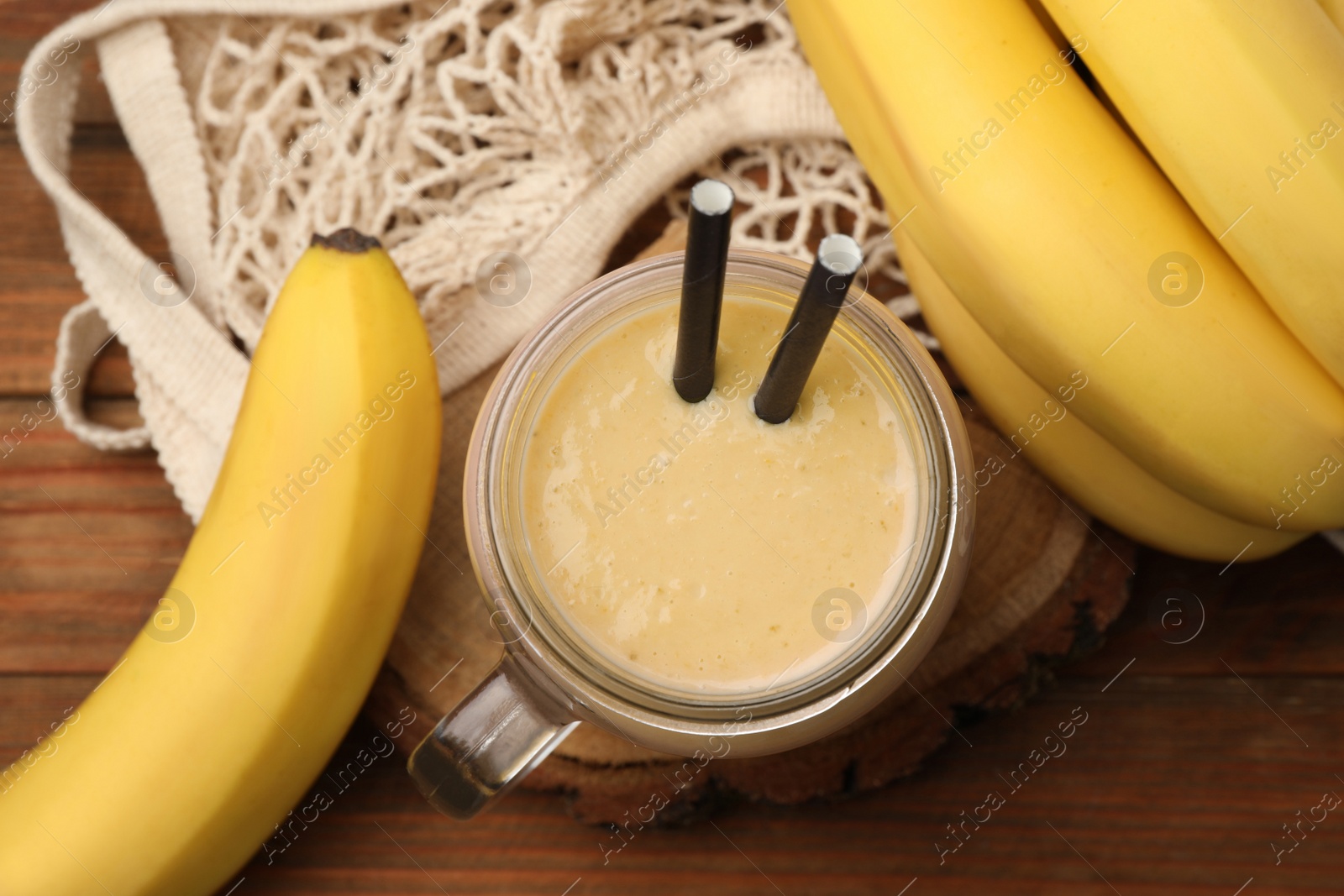 Photo of Mason jar with banana smoothie on wooden table, flat lay