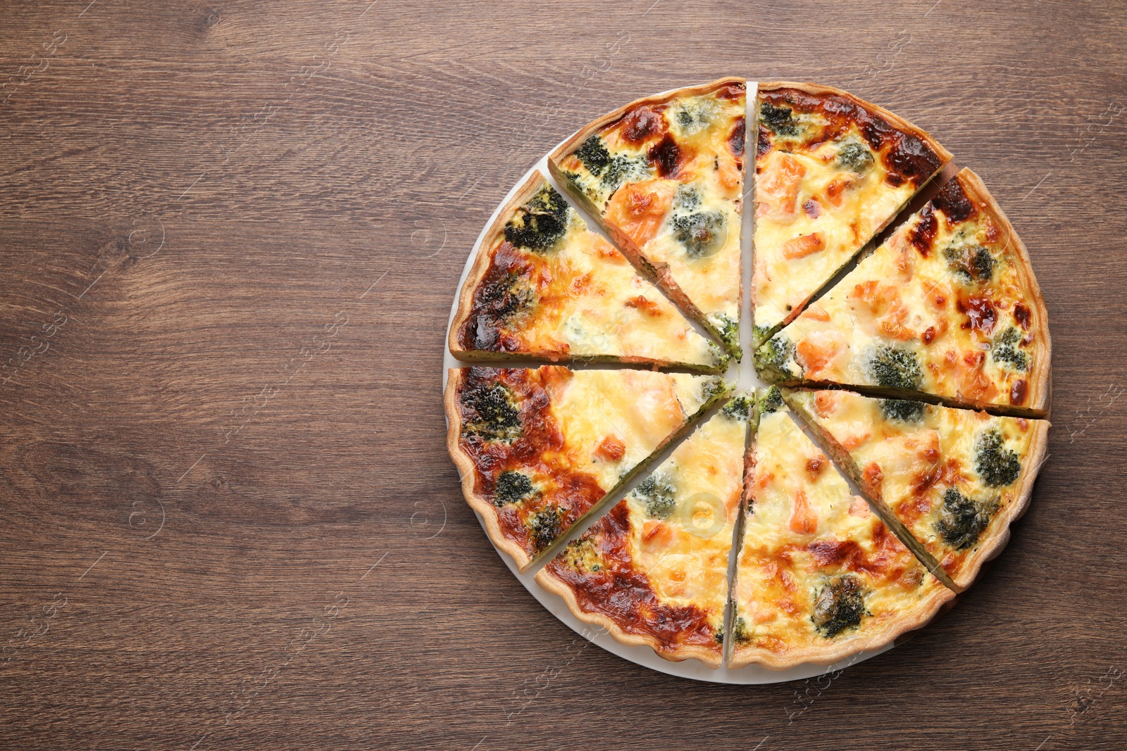 Photo of Delicious homemade quiche with salmon and broccoli on wooden table, top view. Space for text