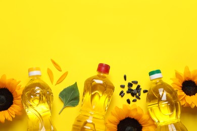 Photo of Bottles of cooking oil, sunflowers and seeds on yellow background, flat lay. Space for text