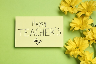Photo of Paper with inscription HAPPY TEACHER'S DAY and flowers on light green background, flat lay