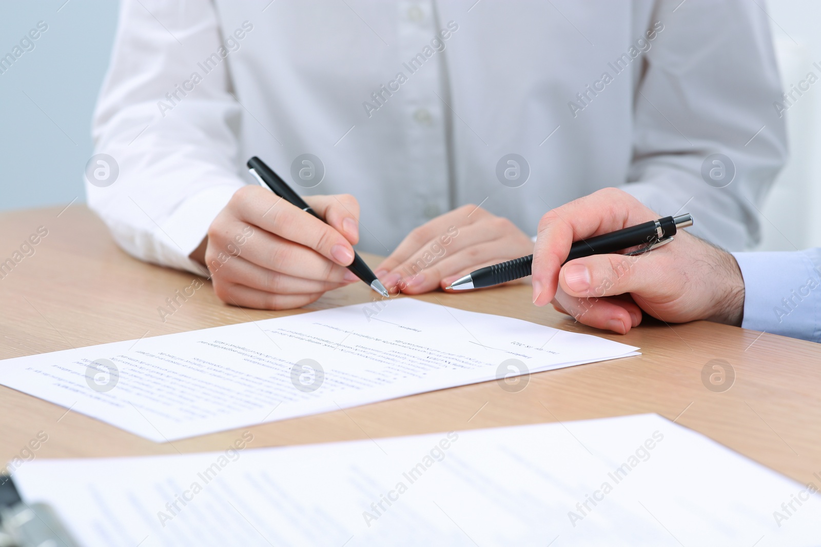 Photo of Businesspeople signing contract at wooden table, closeup of hands