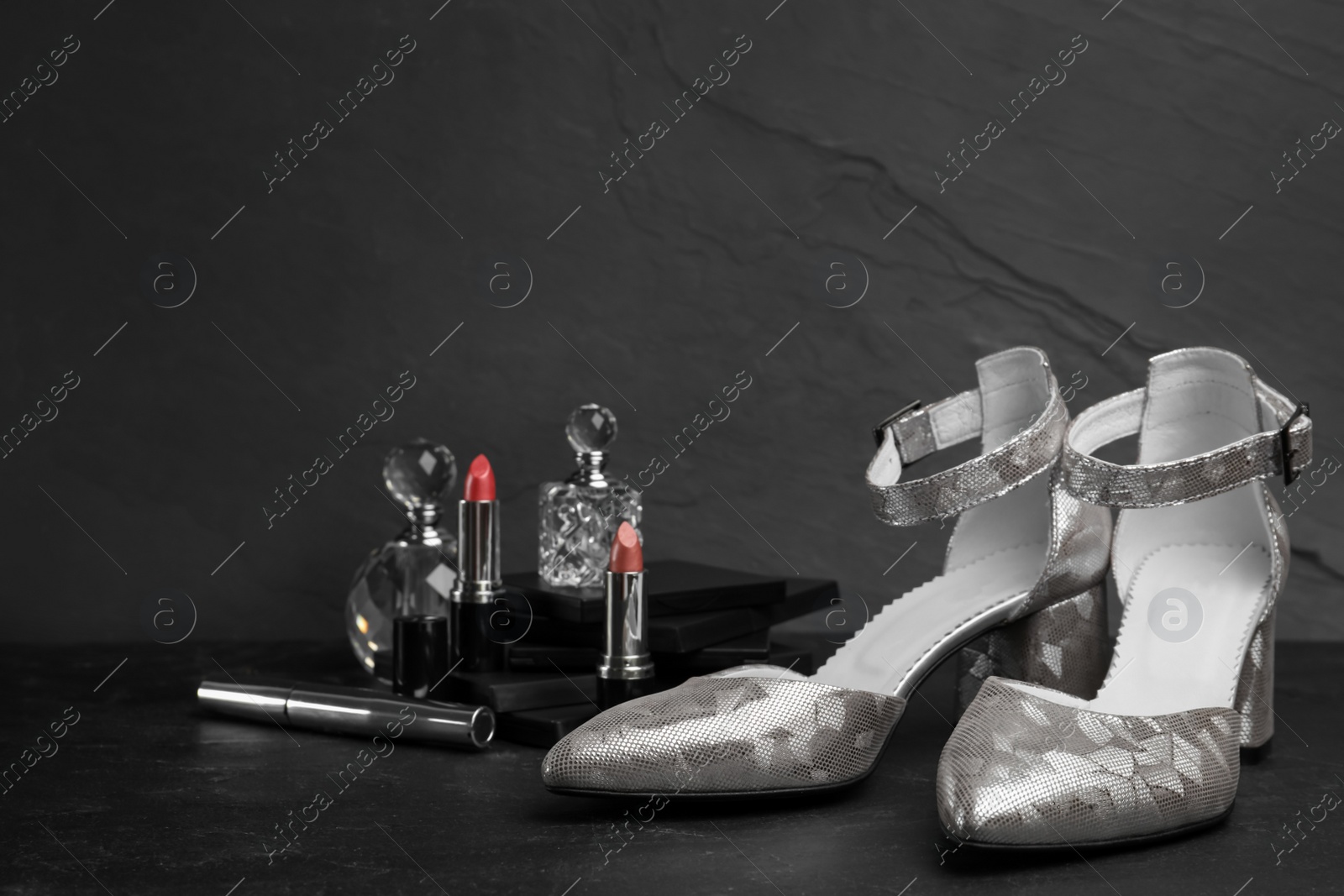 Photo of Composition with stylish silver female shoes on black stone table