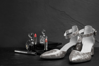 Composition with stylish silver female shoes on black stone table