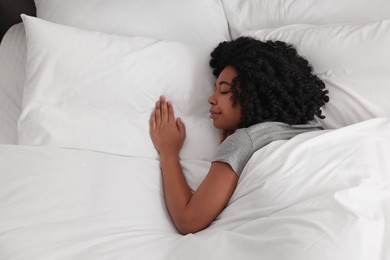 Beautiful young woman sleeping in soft bed, top view