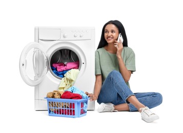 Photo of Beautiful woman talking on phone near washing machine with laundry against white background