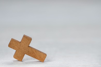 Wooden Christian cross on white table, space for text